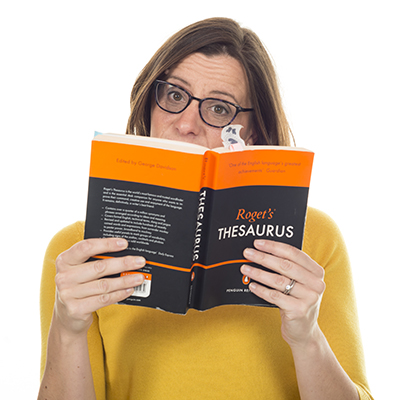 Promotional image of a copy writer peeking over a thesaurus