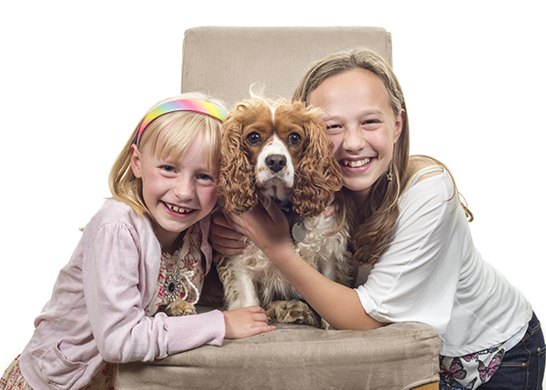 Studio portrait of two girls hugging their dog